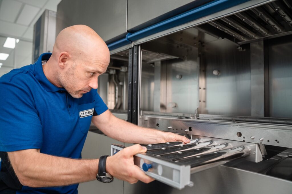 HOBART monteur neemt de wasarm uit een doorschuifvaatwasmachine voor onderhoud