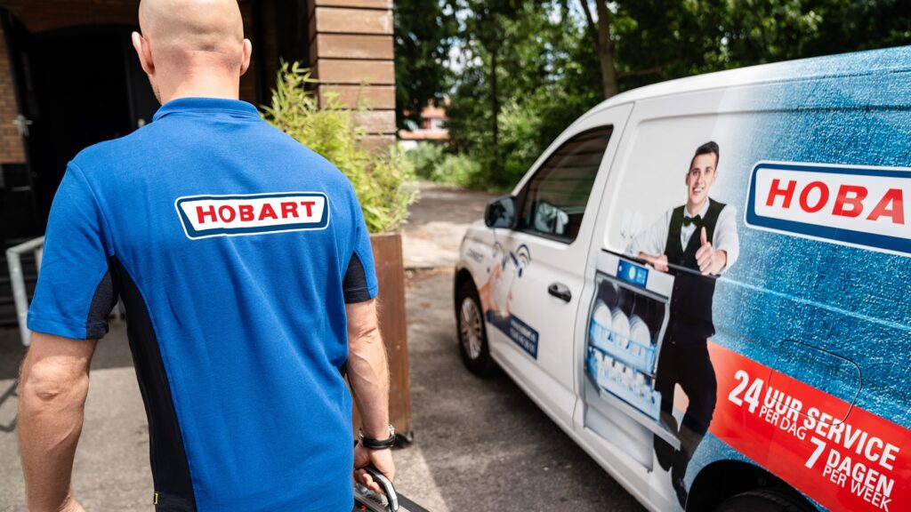 HOBART servicemonteur loopt met gereedschapskoffer naar de servicebus met 24-uursservice